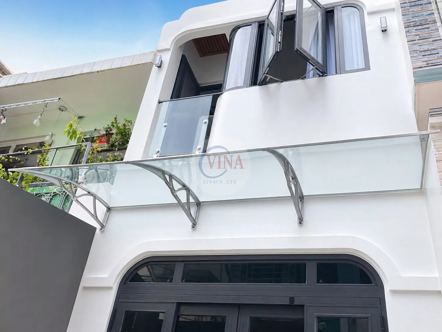 Mái che canopy tay nhôm đúc lắp tại nhà phố, nhìn từ dưới lên trời xanh