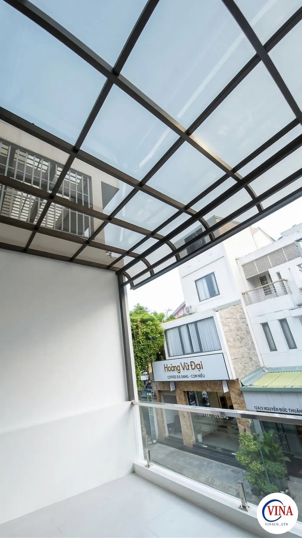 Nhìn từ dưới mái che canopy sân thượng ra dãy nhà phố và quán cà phê hàng xóm