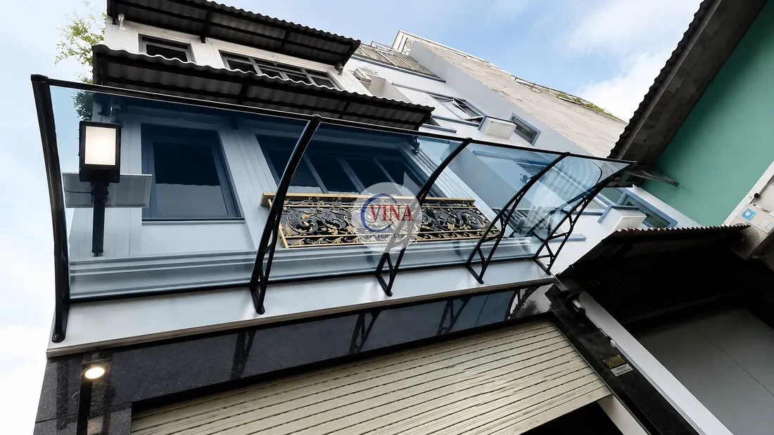 Cận cảnh mái che lấy sáng canopy và lan can sắt mỹ nghệ hoa văn mạ vàng trên ban công