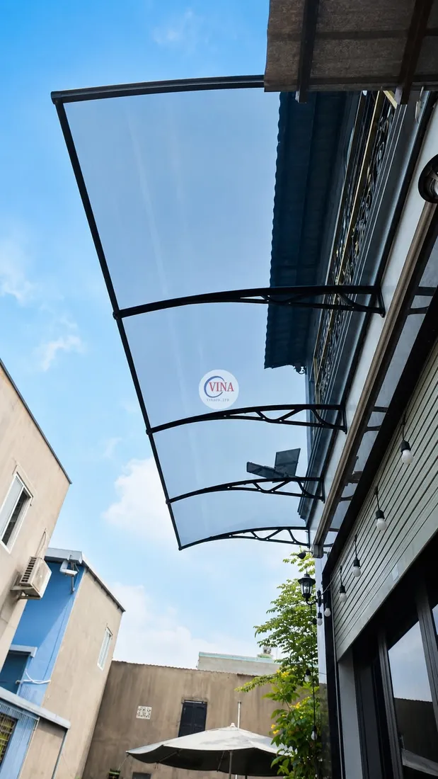 Mái che lấy sáng canopy kéo dài dọc lối đi bên hông nhà, phía dưới treo đèn dây trang trí