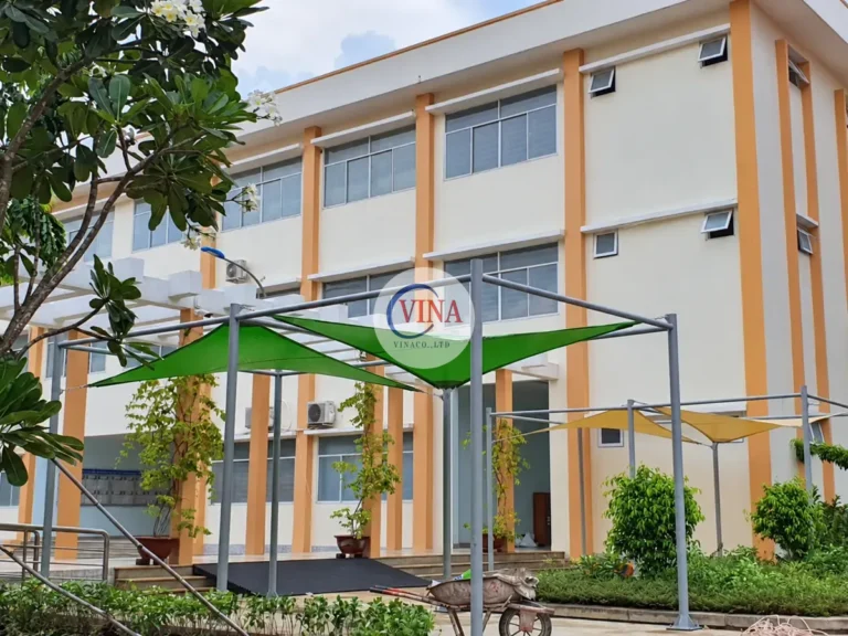 Góc nhìn rộng cho thấy mái bạt xanh đặt giữa sân và dãy phòng học.