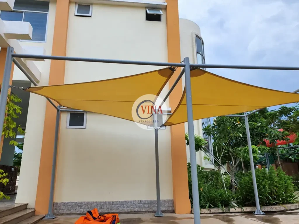 Mái bạt vàng trên hệ cột xám bên cạnh dãy phòng học