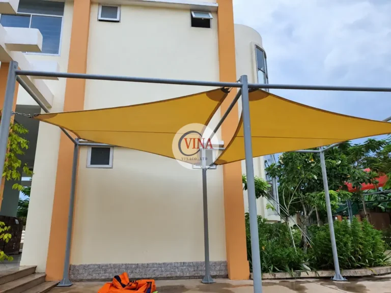 Tấm bạt vàng che khoảng sân sát dãy phòng học, căng trên khung cột màu xám.