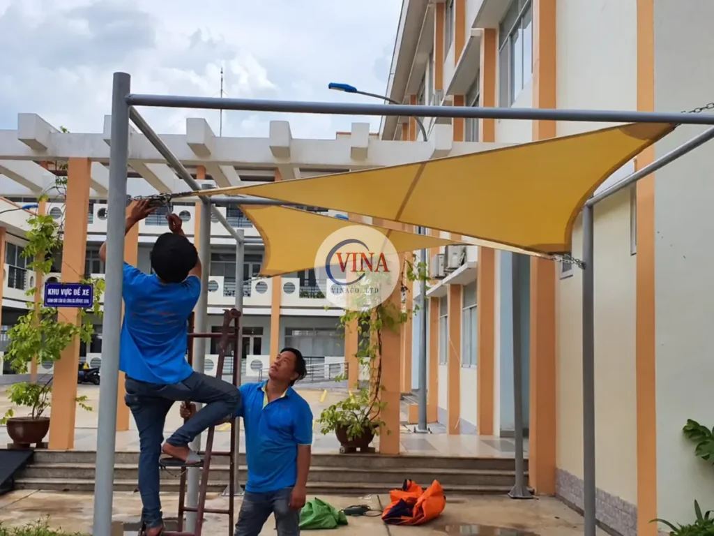 Thợ thao tác ở mép bạt vàng trên khung đỡ tại trường học quận 12
