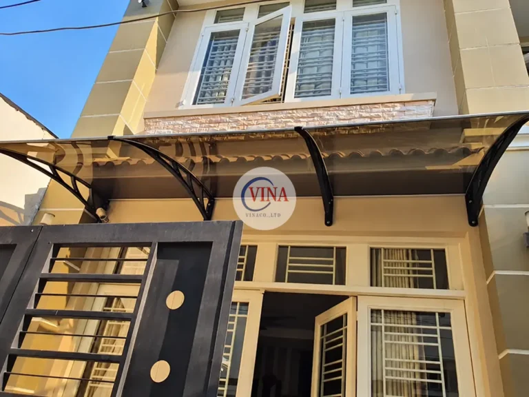 Nhìn chính diện, mái che trải ngang phía trên bộ cửa trắng của nhà phố.