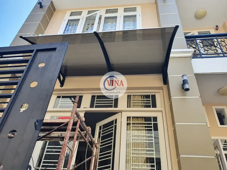 Phần tấm lợp và tay đỡ đã được lắp phía trên cửa, bên dưới còn thang thi công.