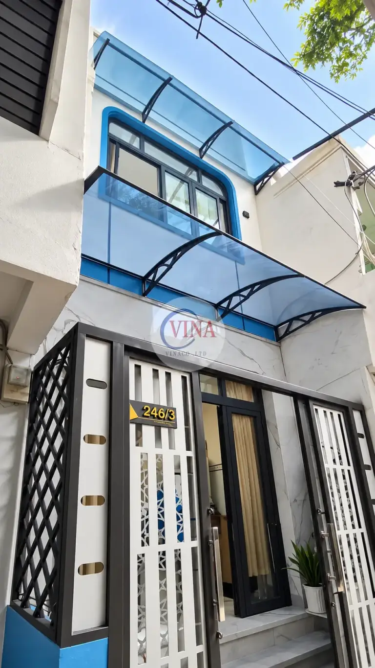 Chụp chéo từ dưới lên: tay đỡ đen dạng vòm có thanh giằng, bắt vào tường phía trên mảng ốp đá.