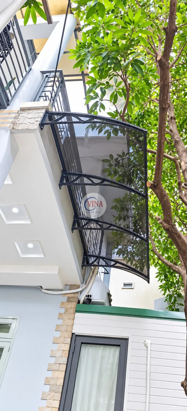 Cận cảnh 4 tay đỡ màu đen chia đều theo chiều dài tấm mái, bắt trực tiếp vào mặt tường ốp đá của ban công.